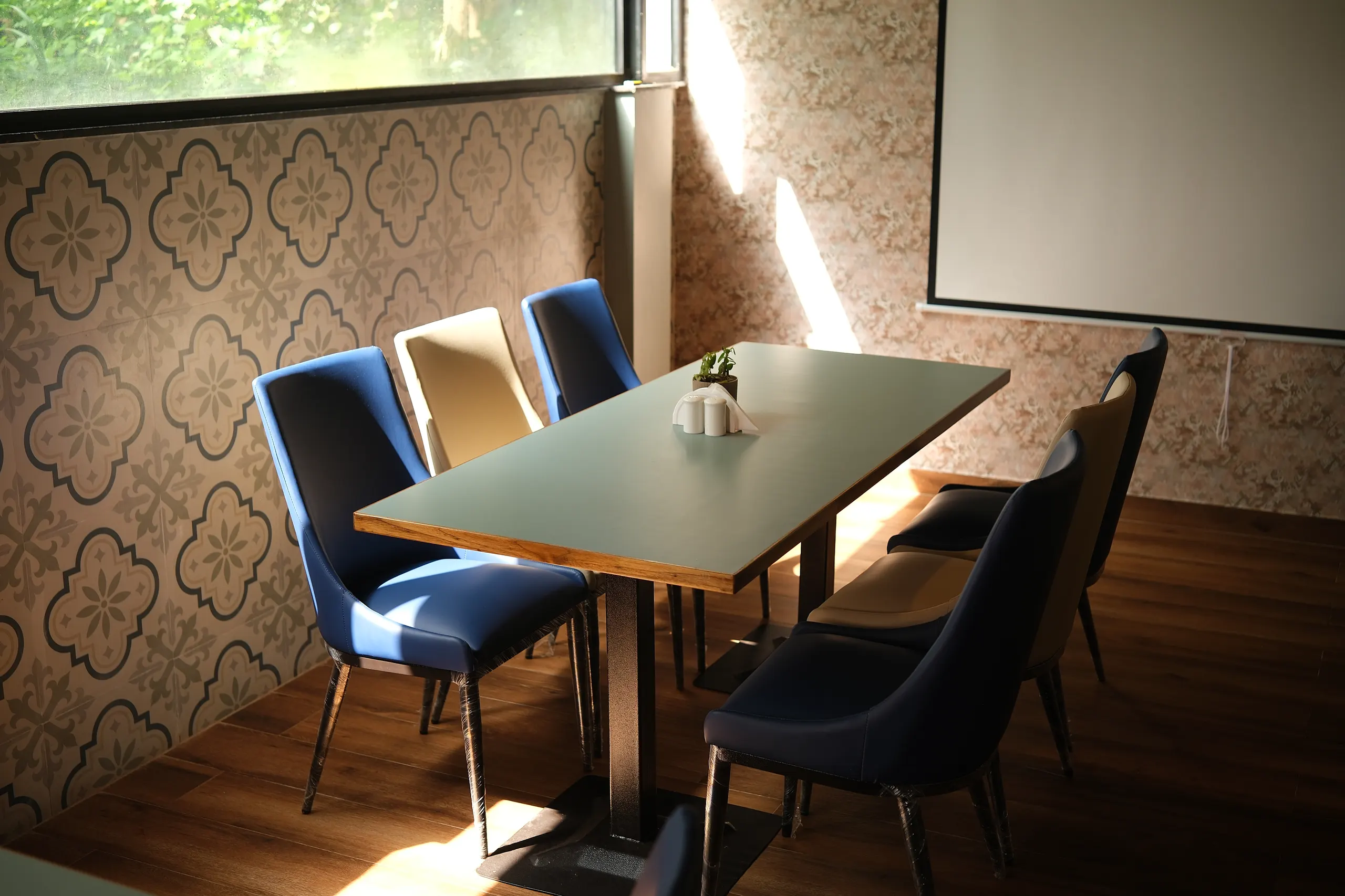 The private dining room, set with a long table, blue and black chairs and a projector screen