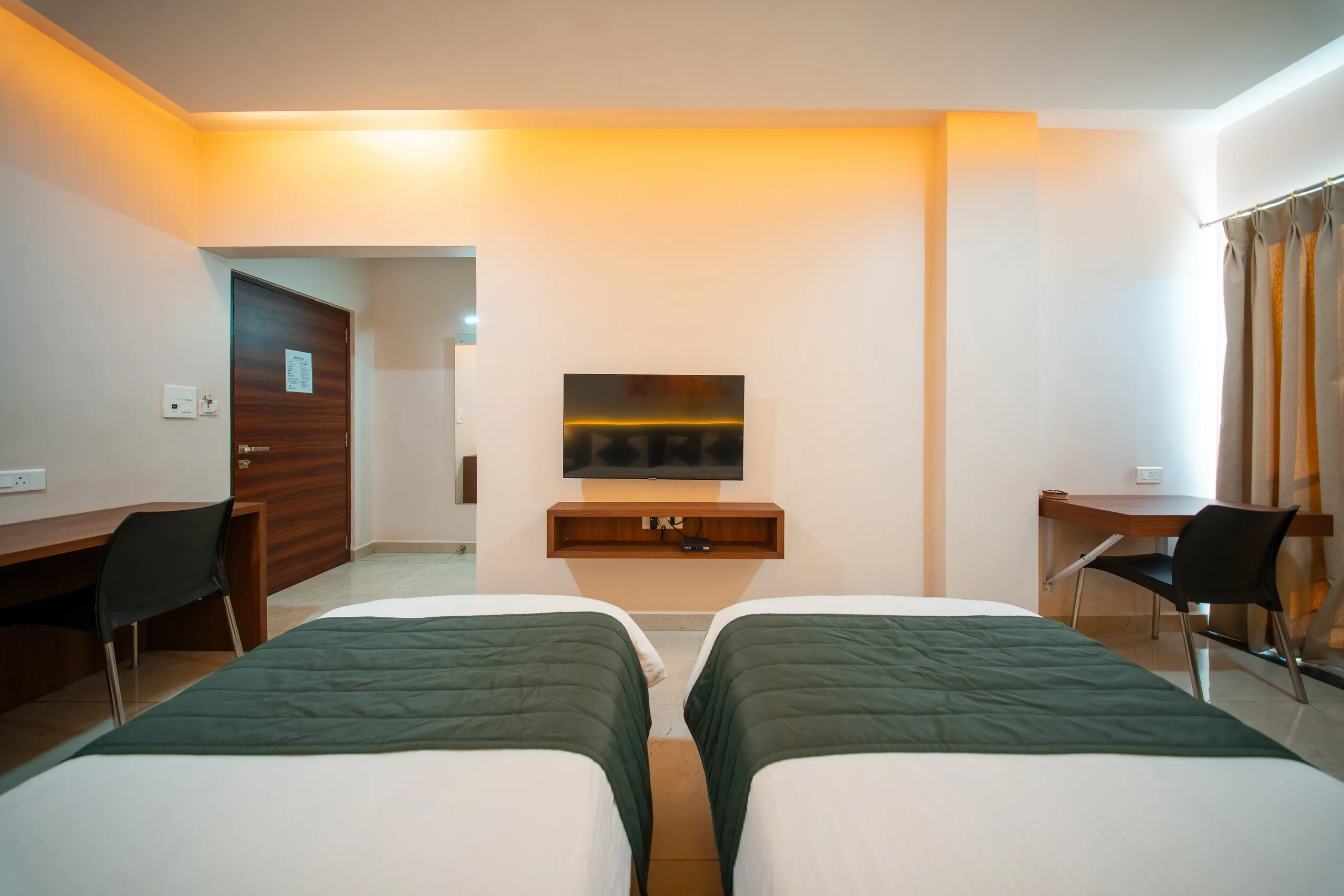 An Executive Twin room with twin beds, wall-mounted television and desk