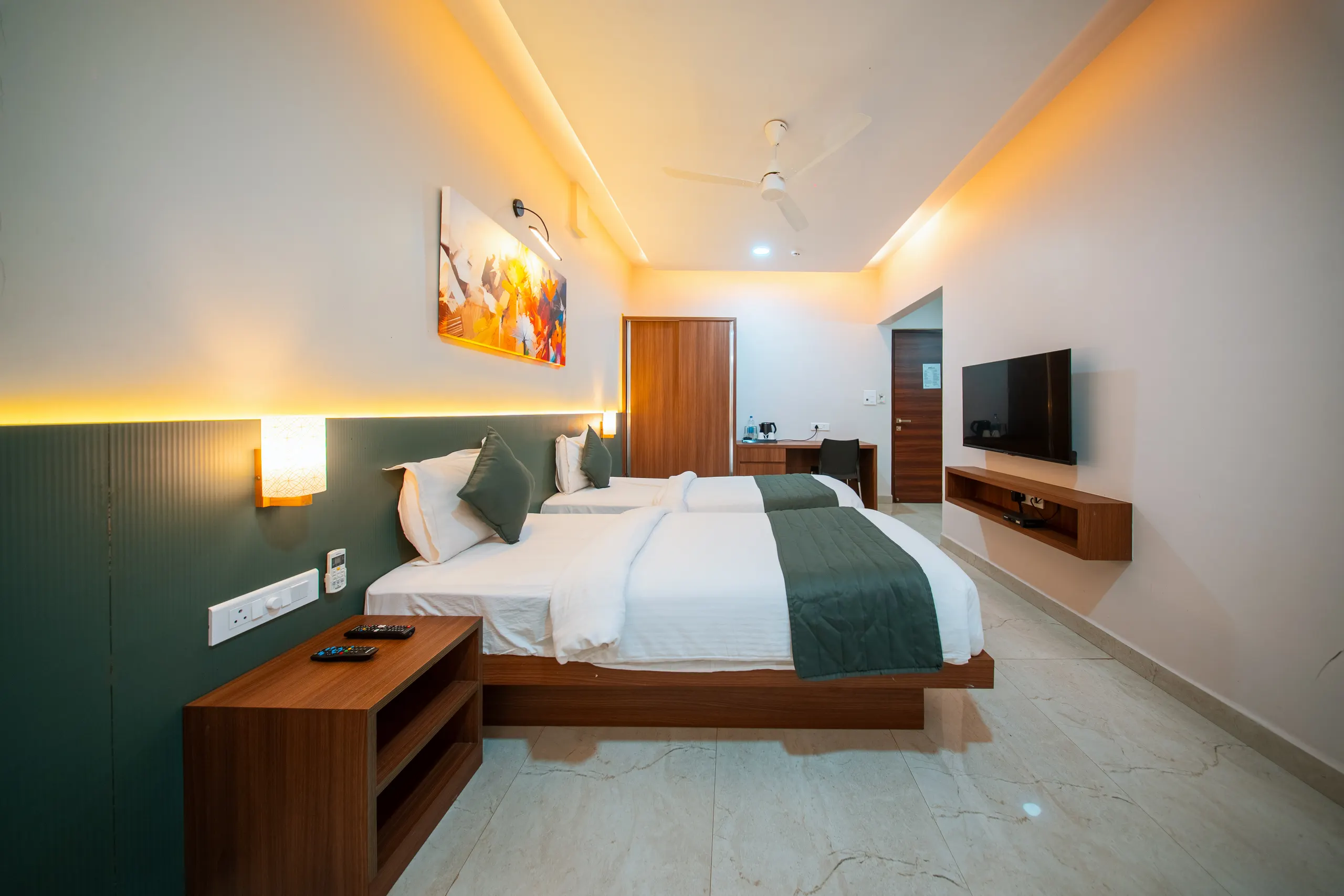 An Executive Twin room with twin beds, a green headboard panel and wall television